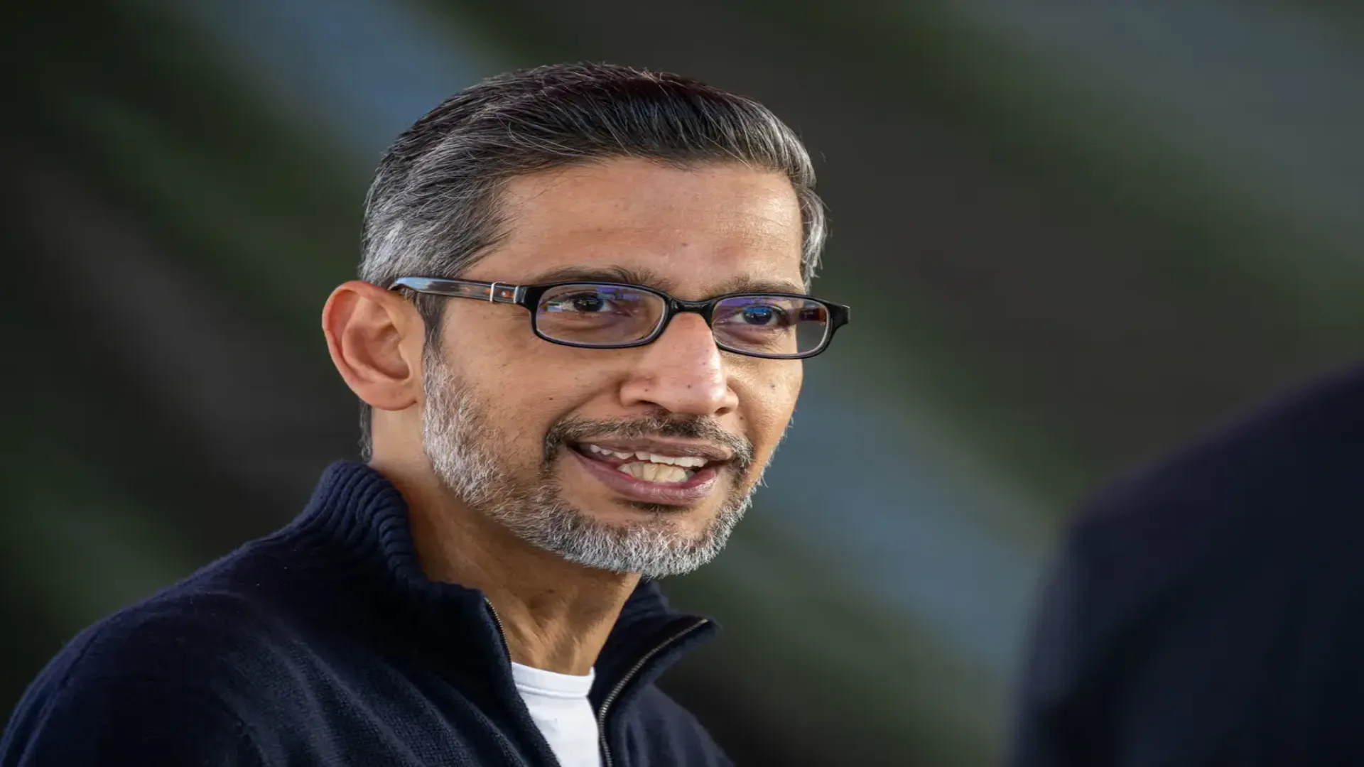 Google CEO Sundar Pichai speaking at a public event as US college graduates protest AI job displacement fears at 2026 commencement ceremonies.